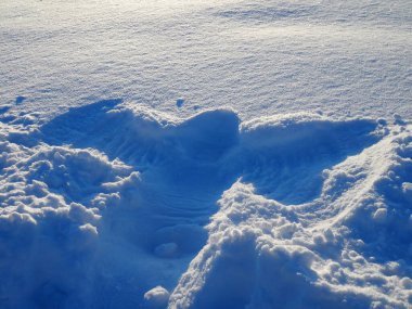 Snow angel on pure and fluffy snow at sunset clipart