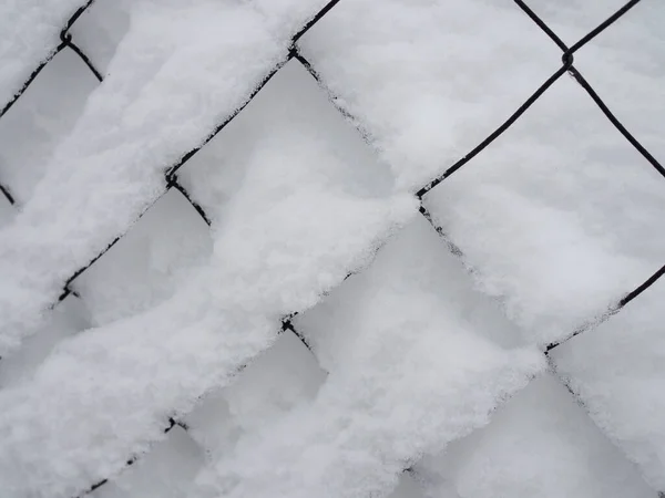 Valla de malla metálica de una pista de tenis cubierta de nieve —  Fotos de Stock