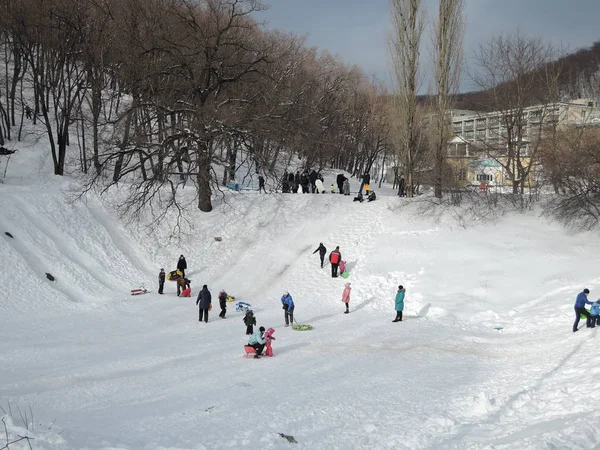 Volwassenen en kinderen sleeën met glijbanen, familie weekend. Rusland, Saratov - januari 2016 — Stockfoto