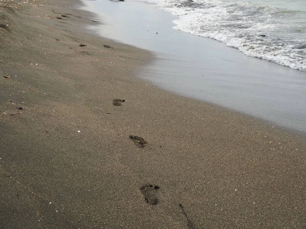 Pegadas de bebê na praia de areia perto do mar. — Fotografia de Stock