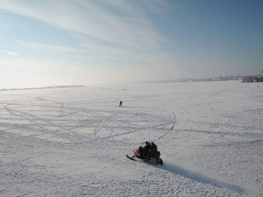 Kar motosikletli kış nehrinde giden iki adam. Rusya, Saratov - Ocak 2016