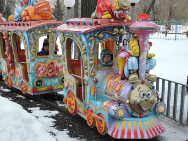 Çocuk eğlencesi - eğlence parkında piposu olan küçük bir tren kışın çocuklara biner. Rusya, Saratov - Ocak 2016