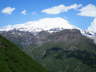 Büyük doğa sıradağları. Beyaz kar dağı veya yeşil alanlar, mavi gökyüzü arka plan ile volkan Elbrus amazing perspektif. Elbrus manzara görünümü - Rusya ve Avrupa'nın en yüksek zirvesi