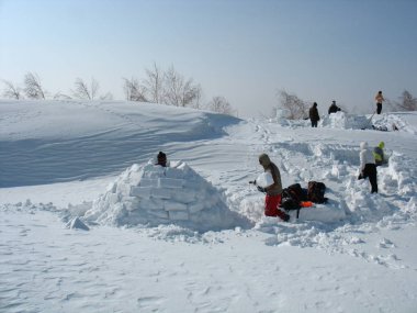 Aile tarlada karlı bir iglu inşa ediyor, kışın eğlenin, Rusya, Saratov - Mart 2012