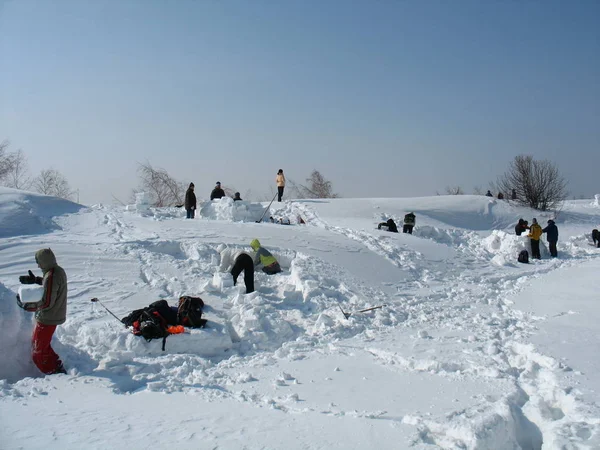 Familie gebouw een iglu met sneeuw in het veld, veel plezier in de winter, Rusland, Saratov - maart, 2012 — Stockfoto