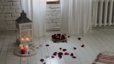 Cam vazoda gül ve mum. Odada çiçekler, mumlar ve gül yaprakları var. Romantik bir akşam