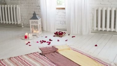 Cam vazoda gül ve mum. Odada çiçekler, mumlar ve gül yaprakları var. Romantik bir akşam