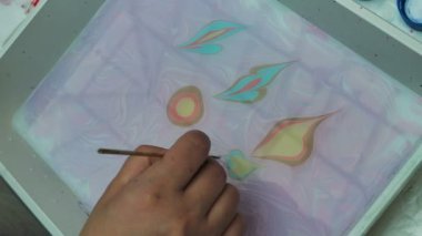 Ebru 'nun resimlerini yapan kadın sanatçı. Sudaki sanat. Fırçayla çizmek ve ardından kağıt baskılar. Dalgalı renkli boyalar. Hobi, sanat, kültür konsepti