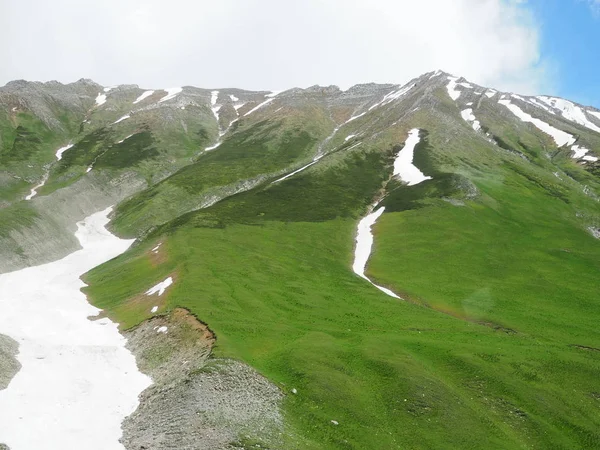 Paisagens deslumbrantes com grama verde, montanhas e neve nos Alpes Suíços . — Fotografia de Stock
