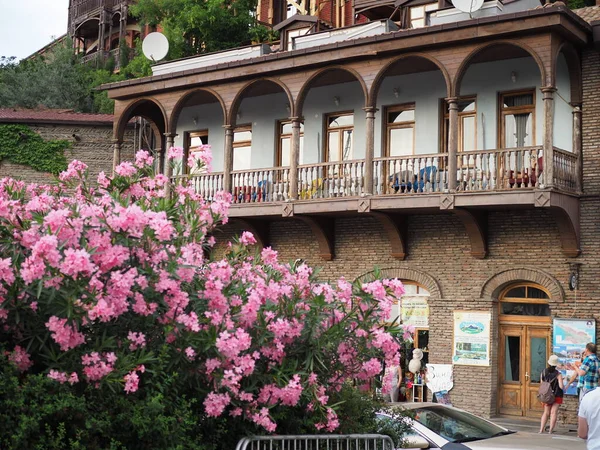 Типичный дом экстерьера старого центра Тбилиси Шабби дом с деревянным балконом, фруктовыми деревьями и кручеными кустарниками. Грузия, Тбилиси-июнь 2019 года — стоковое фото