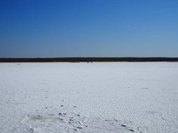 Superfície branca do lago de sal e o céu azul brilhante, pessoas andando na distância — Fotografia de Stock