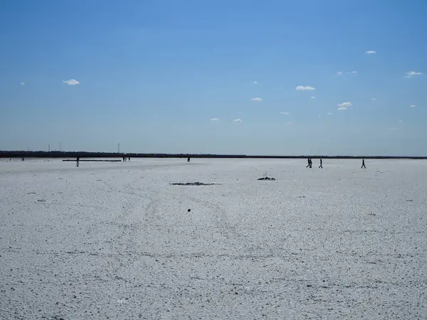 Superfície branca do lago de sal e o céu azul brilhante, pessoas andando na distância — Fotografia de Stock