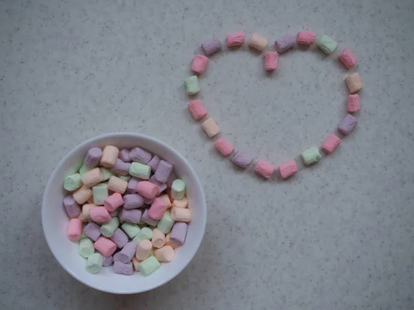 Sammansättning till Alla hjärtans dag den 14 februari. Delikat rosa bakgrund och gula och rosa marshmallows som anges i form av ett hjärta. Gratulationskort. Platt låg, ovanifrån, kopiera utrymme. — Stockfoto