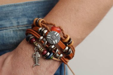 Kolunda erkek etnik bileziği olan adamın elinde kot pantolonun içinde bir bilezik var.