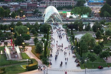 Georgia, Tbilisi - June 2019: Beautiful cityscape of georgian Capital old town Tbilisi. Modern glass Bridge of Peace over the river Kura and tourist crowd in the old part of Tbilisi, Georgia