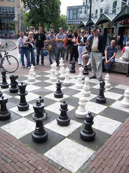 AMSTERDAM, PAÍSES BAJOS - 4 DE AGOSTO DE 2009: La gente jugando ajedrez en la calle con piezas de gran tamaño. Es el ocio querido de los hombres locales . — Foto de Stock