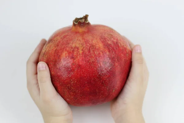 Kinderhände mit reifem Granatapfel auf weißem Hintergrund — Stockfoto