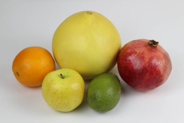 some ripe fruit on a white background: pomegranate, pomelo, orange, avocado, Apple