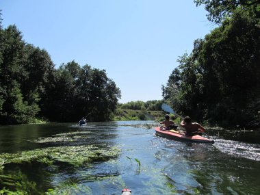 Güneşli bir günde bir grup turist kano üzerinde nehirde rafting yapıyor.