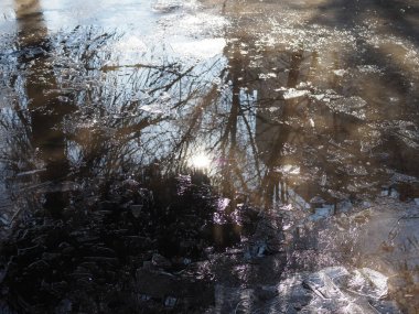 Baharda su birikintileri. Güneş ışınları ve parlaklığı su birikintilerine yansıyor. Kar ve buz eriyor.