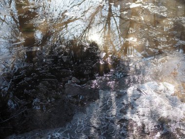 Baharda su birikintileri. Güneş ışınları ve parlaklığı su birikintilerine yansıyor. Kar ve buz eriyor.