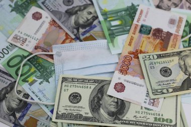 Farklı değerler, dolarlar, avrolar ve Rus rublesi arasında tıbbi maske. 2020 baharındaki küresel ekonomik krizin nedeni olarak Coronavirus.