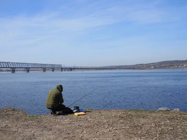 Jovem Pescador Capuz Verde Senta Margem Rio Perto Ponte Primavera — Fotografia de Stock