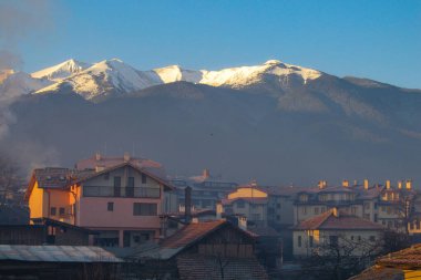 Bulgaristan 'ın Bansko kentinde gün batımında ev manzarası ve güzel dağlarla manzara