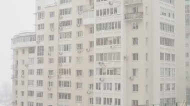 Yeni, modern tuğla bir apartmanın önünde kar yağışı. Pencereden manzaralı..