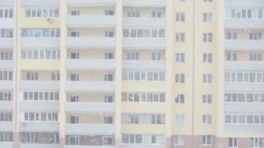Yeni, modern tuğla bir apartmanın önünde kar yağışı. Pencereden manzaralı..