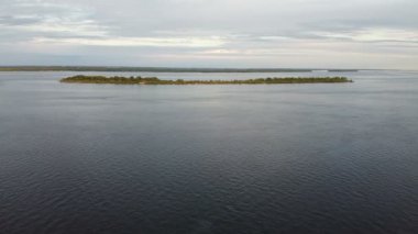 Gün batımında doğal manzarada sahilin hava aracı görüntüsü. General Panorama, nehir kıyısındaki kum ve orman sahillerinde uçuyor. Nehrin ortasında ıssız bir ada.