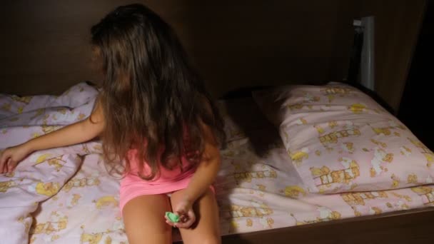 Dziewczyna wkłada ząb do futerału pod poduszkę. Ząb dla zębowej wróżki. Dziewczyna siedząca na łóżku i przygotowująca się do snu. Pokazuje pudełko z zębami przed kamerą. Rama środkowa. — Wideo stockowe