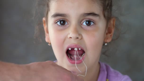 Руки взрослого человека тянут за нитку, привязанную к зубу ребенка. Успешная попытка удалить зуб. Вырви зуб ниткой. Удалите зуб дома. Портрет — стоковое видео