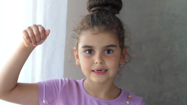 Portrait d'un enfant édenté souriant tenant une dent sur une ficelle. Tentative réussie d'enlever une dent. Retirez la dent avec un fil. Retirer la dent à la maison . — Video