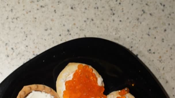 Red caviar is put with a spoon on tartlets with cottage cheese. Preparation of snacks with red caviar. Top view. Frame movement from top to bottom. Slider. Close up — Stock Video