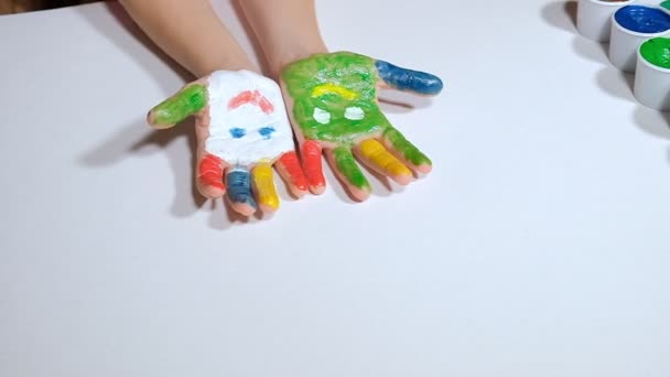 Een klein meisje tekent met gekleurde vingerverf op een wit papier — Stockvideo