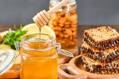Bal, bal peteğinde ahşap bir tabakta ve altın bal kavanozda fındık ve bal için tarakta limon ve zencefil