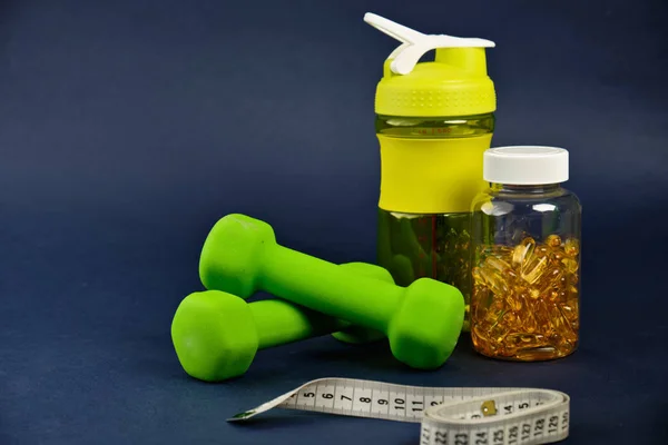 Plastikowy shaker, zielone hantle i puszka omega 3 na niebieskim tle — Zdjęcie stockowe