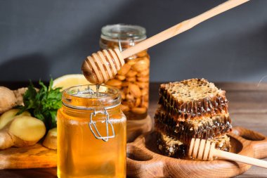 Bal, bal peteğinde ahşap bir tabakta ve altın bal kavanozda fındık ve bal için tarakta limon ve zencefil