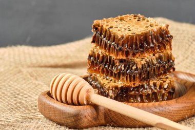 Tahta bir tabakta bal kovanında bal, ahşap bir zeminde bal kaşığı..