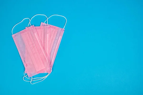 Many medical masks on the blue colored background to cover the mouth and nose for protection from virus and bacteria. Epidemic concept. Regular pattern,