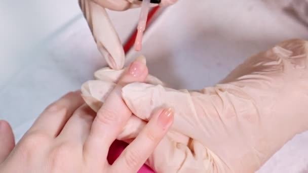 Manicura maestro aplicar esmalte de uñas de color rosa a los clientes uñas en un salón de belleza. De cerca. . — Vídeos de Stock