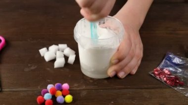 Evde sümük yapıyoruz. Yapıştırıcıdan popüler çocuk oyuncakları yapmak çocukların ellerinden mavi arka planda sümükten oyuncak yapmak..