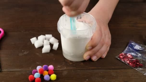 Hacemos limo en casa. haciendo juguetes infantiles populares de pegamento.. Las manos de los niños hacen un juguete de limo sobre un fondo azul . — Vídeos de Stock