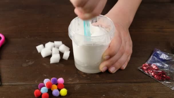 On fait de la boue à la maison. fabrication de jouets populaires pour enfants à partir de colle.. Les mains des enfants font un jouet à partir de boue sur un fond bleu . — Video