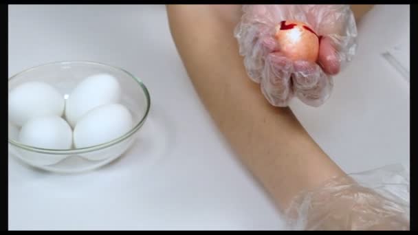 Handschuhhände bemalen Ostereier auf weißem Hintergrund. — Stockvideo