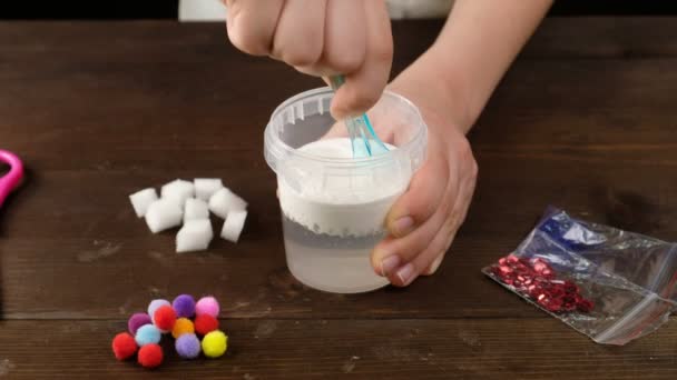 Wir machen Schleim zu Hause. Herstellung beliebter Kinderspielzeuge aus Klebstoff.. Kinderhände machen ein Spielzeug aus Schleim auf blauem Hintergrund. — Stockvideo