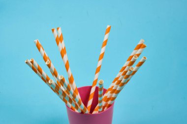 Mavi arka planda içecekler için plastik tüpler. Plastik ve ekolojinin çevre kirliliği kavramı. Seçici odak, metin için alan