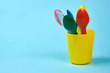 Mavi arka planda çok renkli plastik tabaklar. Plastik ve ekolojinin çevre kirliliği kavramı. metin için yer,