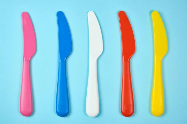 Multicolored plastic dishes on a blue background. The concept of environmental pollution by plastic, ecology. place for text,